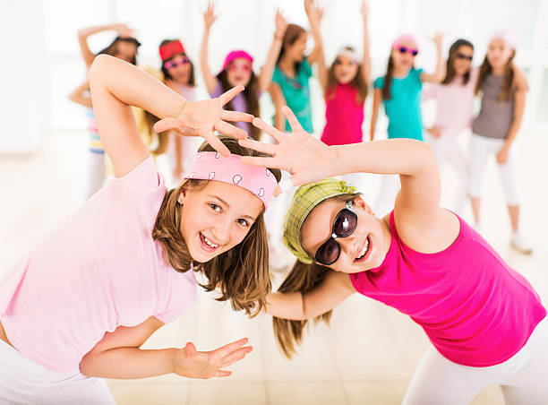 Little girls dancing. Group of little girls dancing. Focus is on foreground, on two girls in a dance move looking at the camera.    dance troupe stock pictures, royalty-free photos & images