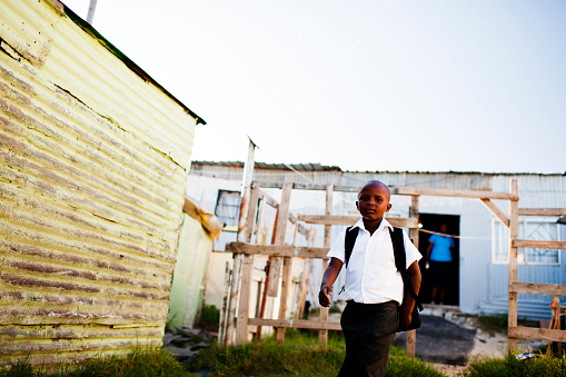 Young boy in school uniform leaving his township home to school