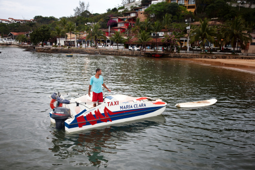 Buzios, Brazil - November 15, 2012: Man arriving in his Water taxi in the harbour in the Brazilian seaside resort of Buzios