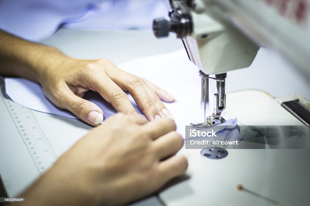 Sewing machine Hand on sewing machine. Adult Stock Photo