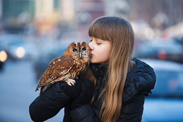 Cute girl standing with little owl on the street of city