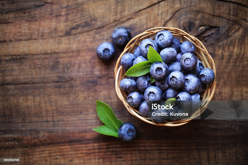 Fresh blueberries Fresh ripe garden blueberries in a wicker bowl on dark rustic wooden table. with copy space for your text Blueberry Stock Photo