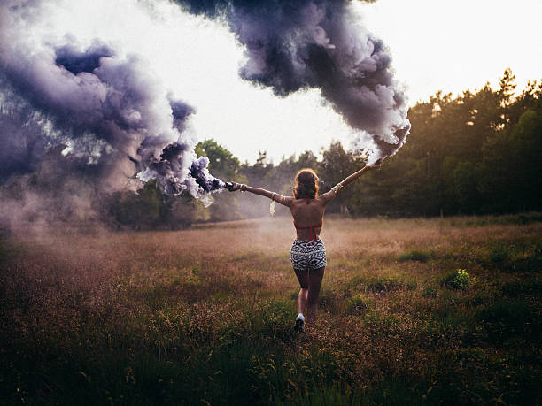 menina hippie correr através do campo com foguetes de fumo roxo - child rear view running nature imagens e fotografias de stock