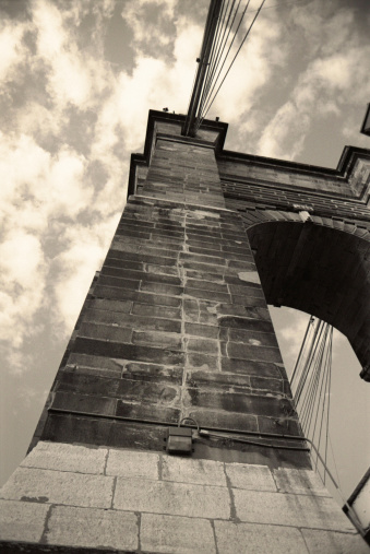 Towering view of one of the historic stone/brick towers of John A. Roebling suspension bridge, c.1866, Cincinnati, Ohio. Vintage image with noise & sepia toning added for retro look.