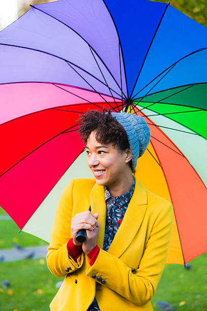 istock Young pretty woman under multicolored umbrella in a park 483227425