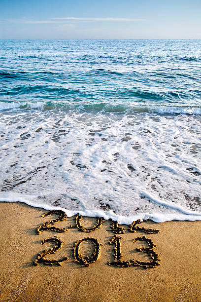 2013 und 2012 schriftliche in sand und wellen - 2013 beach new years eve new years day stock-fotos und bilder