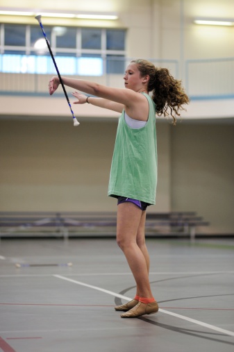 Young teenage girl in gymnasium practicing baton twirling for majorette.