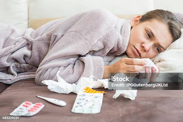 Sad Woman With Tissue And Medicines Lying On Bed Stock Photo - Download Image Now - 20-24 Years, 20-29 Years, Adult