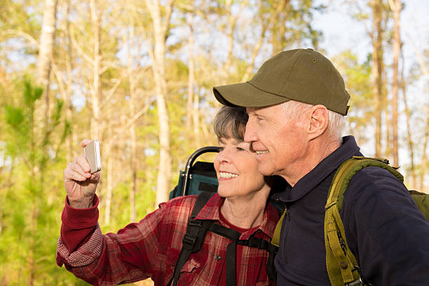 アクティブシニア屋外のカップルのハイキングで森携帯電話'selfie'ます。 - autumn senior adult mature couple active seniors ストックフォトと画像