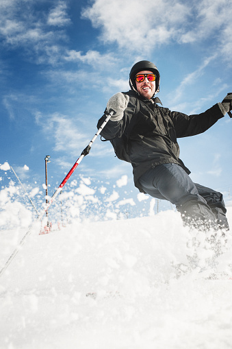 Man skiing in the ski slope with ski lift in the background