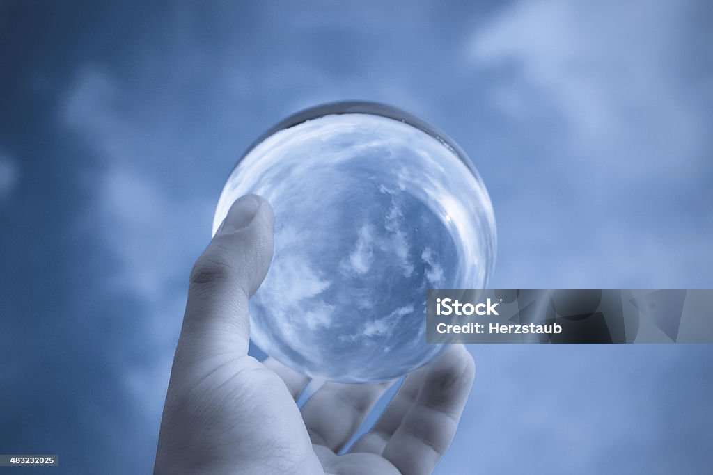 Ball to the sky A glass ball held to the sky Blue Stock Photo