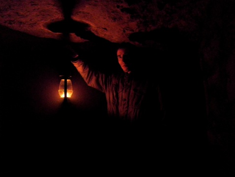 Mysterious man holding a lamp in underground chamber.