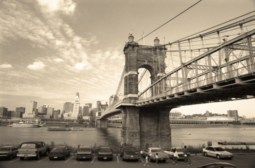 John A. Roebling suspension bridge, c.1866, spans 1057 ft. & is on the US National Register of Historic Places. Seen here facing the Cincinnati, Ohio skyline. Vintage image with noise & sepia toning added for retro look.