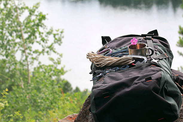 istock Backpack, mug of tea and a flower lying on a rock 483239576