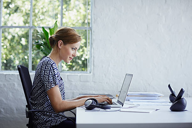 woman working on computer - side window foto e immagini stock