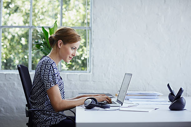 woman working on computer - side view audio стоковые фото и изображения