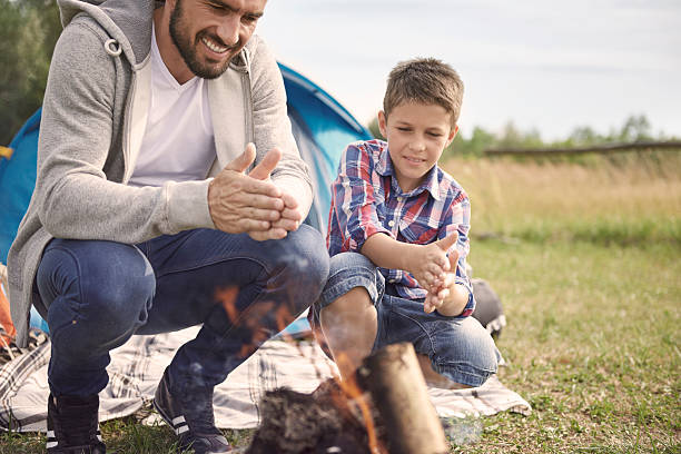istock Father and son rubbing hands over the campfire 483256698