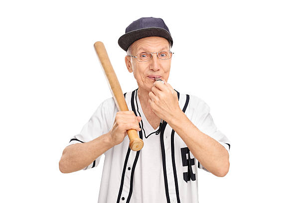 Senior holding baseball bat and blowing a whistle Studio shot of a cheerful senior holding baseball bat and blowing a whistle isolated on white background old baseball stock pictures, royalty-free photos & images