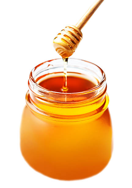 istock Honey in a glass jar with  dipper  isolated on white 483258436