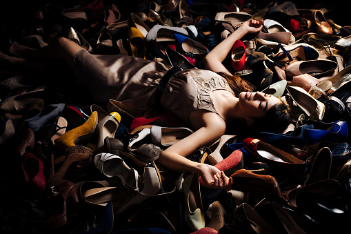 Smiling woman lying on high heels in a store