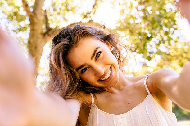 istock Young woman taking a selfie in the park 483264307