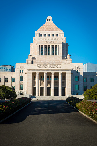 Green spring foliage and clear blue skies framing the monumental stone facade of the Japanese legislative building, Kokkai-gijido, meeting place of both assemblies of the Diet, the House of Representatives in the left wing and the House of Councillors in the right, Chiyoda, Tokyo. ProPhoto RGB profile for maximum color fidelity and gamut.