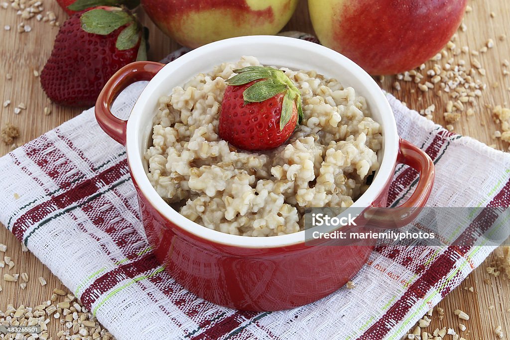 Oatmeal with apples and strawberries Oatmeal in red bowl with apples and strawberries on wooden block Apple - Fruit Stock Photo