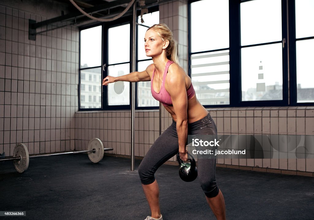 Atletica giovane donna esercizio con kettlebells - Foto stock royalty-free di Adulto