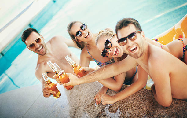 pessoas com cervejas à beira da piscina. - drinking couple bar counter bar - fotografias e filmes do acervo