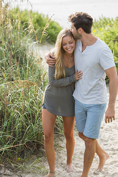 Young romantic couple walking on beach sand dunes