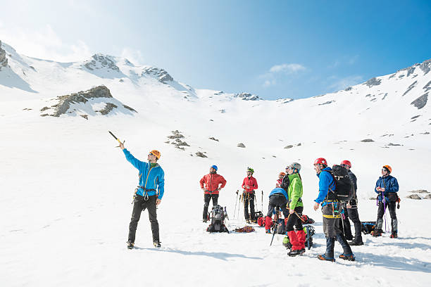 Mountaineering Group of mountaineers preparing to climb up to the mountain peak. Their leader showing them the way.  group of people people recreational pursuit climbing stock pictures, royalty-free photos & images