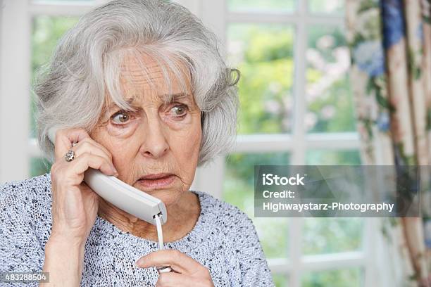 Worried Senior Woman Answering Telephone At Home Stock Photo - Download Image Now - Senior Women, Worried, Using Phone