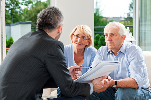 Senior couple having meeting with financial advisor or insurance agent at home.