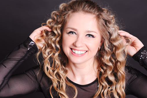 Close up portrait of smiling young woman in studio at black background