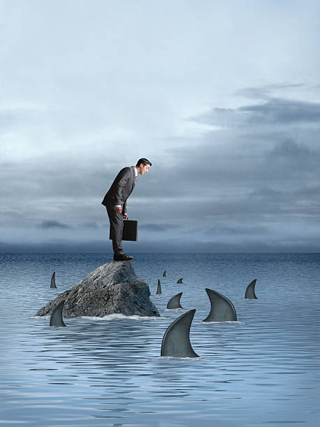 istock Businessman staring down at sharks circling around him 483292231
