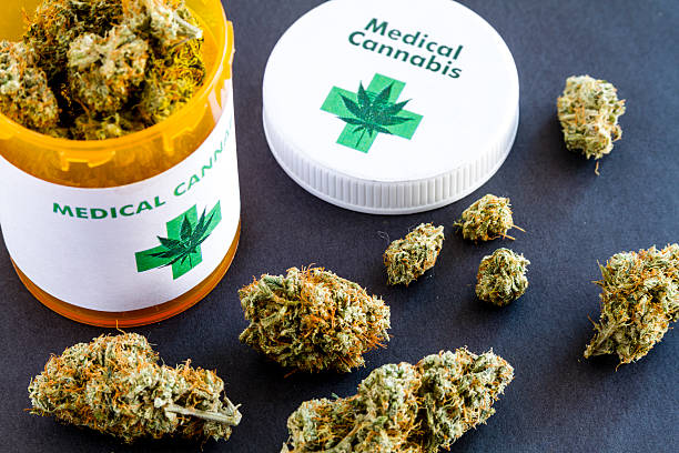 Medical Marijuana Buds on Black Background Medical marijuana buds in large prescription bottle with branded cap on black background legalization photos stock pictures, royalty-free photos & images