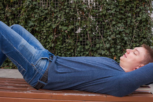 istock Student rests with a book on wooden bench in summer. 483301126