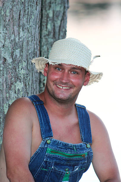 istock Man Wearing Straw Hat and Overalls Poses by Tree 483302212