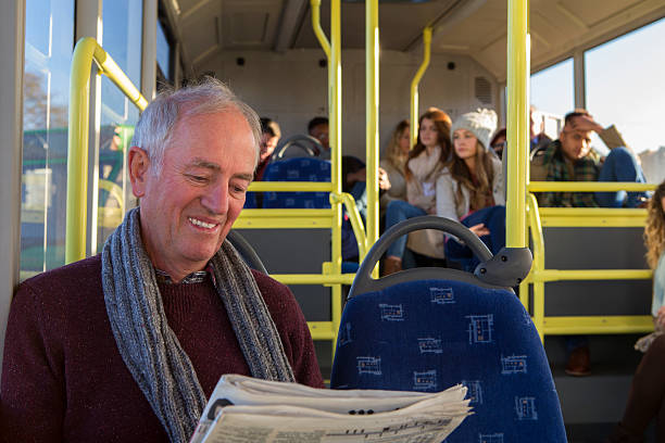 Happy senior man reading a newspaper on the bus.