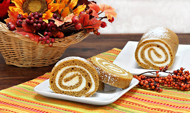 Pumpkin Roll Cake in an Autumn setting. Pumpkin roll cake, whole and sliced, in a fall setting. bittersweet berry stock pictures, royalty-free photos & images