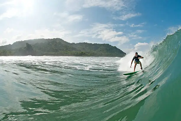 A surfer rides a perfect point break wave just off the jungles of Costa Rica