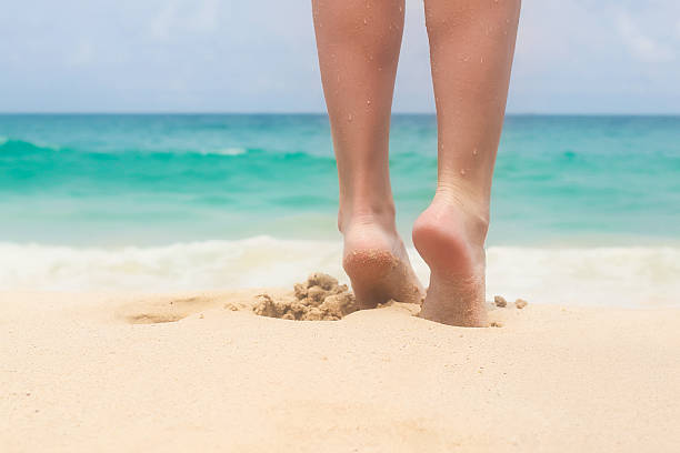 istock Women's beautiful smooth legs on white sand beach 483318181