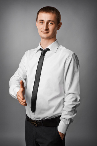 Good-looking young businessman giving hand and smiling