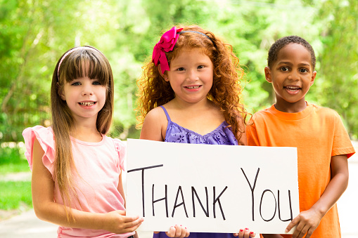 Three beautiful multi-ethnic children saying Thank You to a special someone or charity group.  