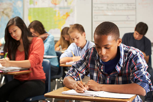 estudante do sexo masculino escrevendo no caderno em sala de aula - high school high school student classroom group of people imagens e fotografias de stock