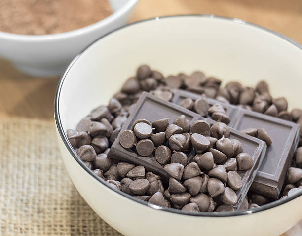 istock Chocolate chips and Dark chocolate bar in white bowl. 483331412