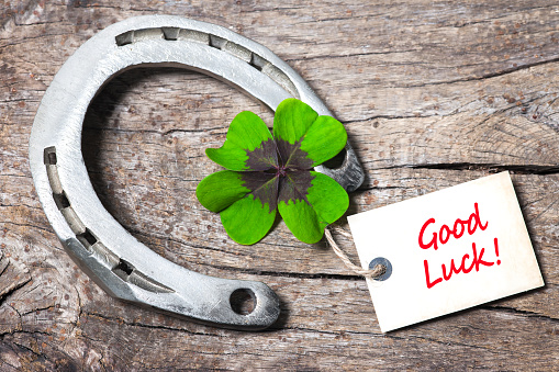 Horseshoe, Leafed clover and tag with good luck on wooden board