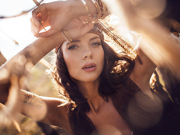Beauty portrait of a boho girl in afternoon sunlight Closeup beauty portrait of a wild looking boho girl gazing at the camera in golden afternoon sunlight bohemian fashion stock pictures, royalty-free photos & images