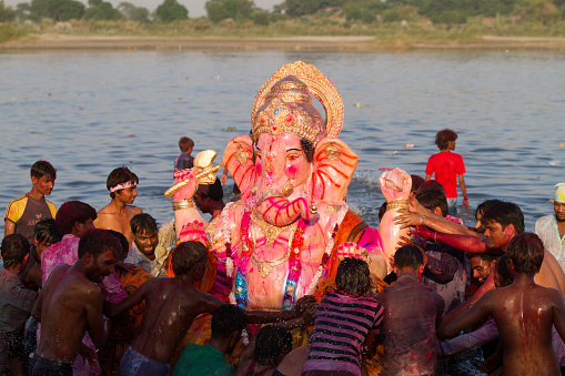 New Delhi, India - September 29, 2012. Hindu devotees immerse an idol of elephant-headed Hindu god Ganesha in the Yamuna river at the conclusion of the Ganesha festival. During the Ganesh Festival Hindu devotees bring home idols of Lord Ganesha and offer prayers in temporary temples in order to invoke his blessings for wisdom and prosperity, culminating with the immersion of the idols in bodies of water.