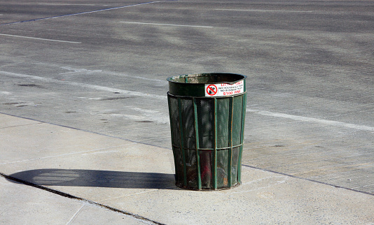 Classic green city trash can with shadow on side of road - room for copy and headline above and below. 